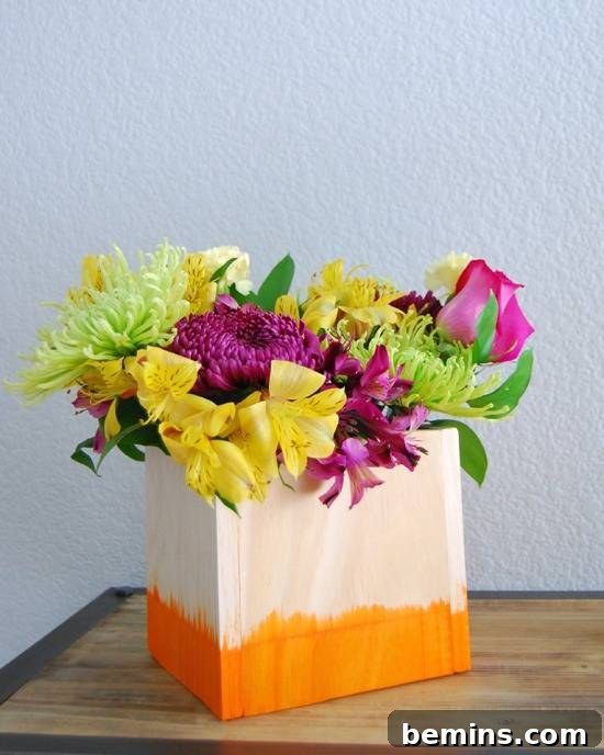 A pink bag with an orange bottom is filed with a boquet of flowers.
