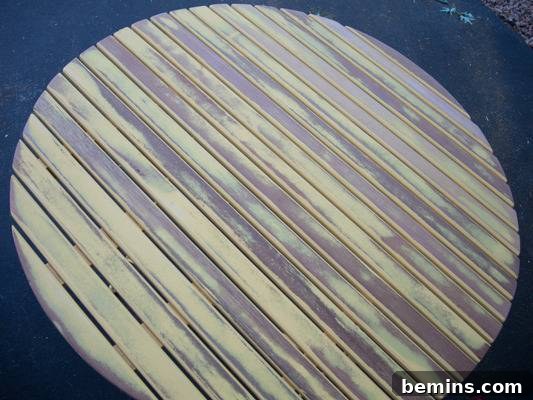 A round table is made out of wooden slats. Removing old paint with an orbital sander.