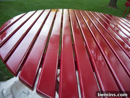 A slatted red table that is sitting in a park. The transformed bistro table is taking shape.