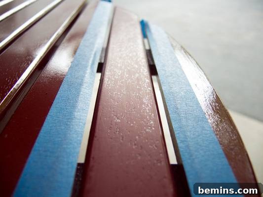 Painted maroon bench seat with blue masking tape. The repaired slat looks smooth and even.