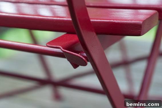 A red metal and wood chair has a locking mechanism. Adding tubing to protect the finish from rubbing.