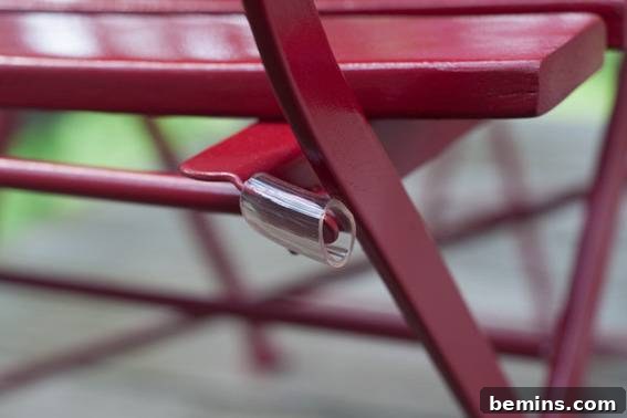A wooden bench outside, that has been painted a cherry red. Protecting the finish with tubing.
