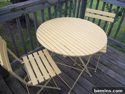 A small, round, slatted outdoor dining table and chairs sit on a deck. Before the makeover: a faded yellow bistro table.