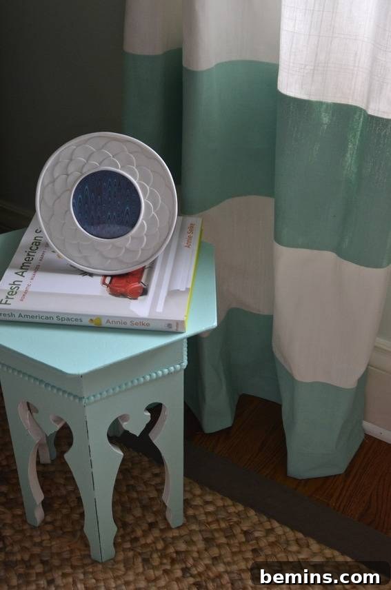Painted Stripes: A Curtain Refresh 15 A book is sitting on a light blue table near a blue and white curtain, showcasing the stylish details of the DIY striped curtains and their surroundings.