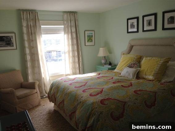 Painted Stripes: A Curtain Refresh 3 A bedroom with light green walls, a large headboard on a bed, and an armchair, illustrating a well-decorated space that inspires curtain customization.