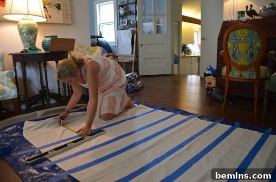 Painted Stripes: A Curtain Refresh 7 A woman is marking on a tarp with a tape measurer, highlighting the process of accurately marking the curtains for stripe placement.