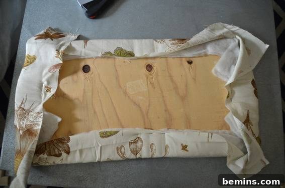 Material being wrapped around the wooden board for upholstery