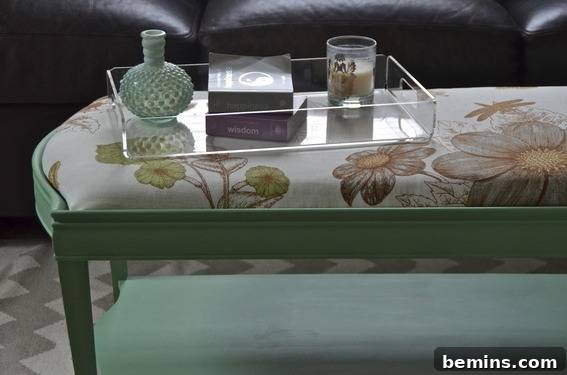 A glass tray sits on the green ottoman, showcasing its function as a coffee table