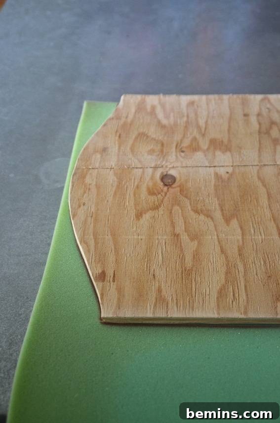 A wooden board sitting on a green cloth, ready to be wrapped with foam and fabric