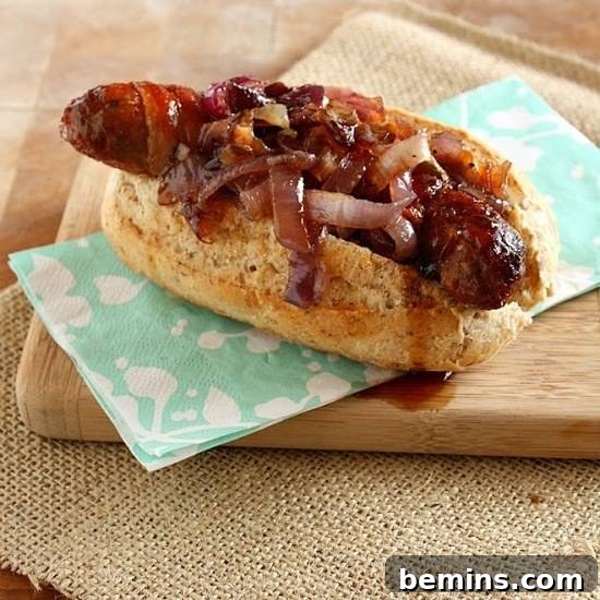 A hot dog coverd in onions on an open bun sitting on a green and white napkin on a cutting board on a piece of burlap.