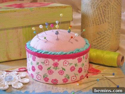 A charming pincushion crafted from a tuna can, featuring fabric and pins, sits next to a spool of thread.