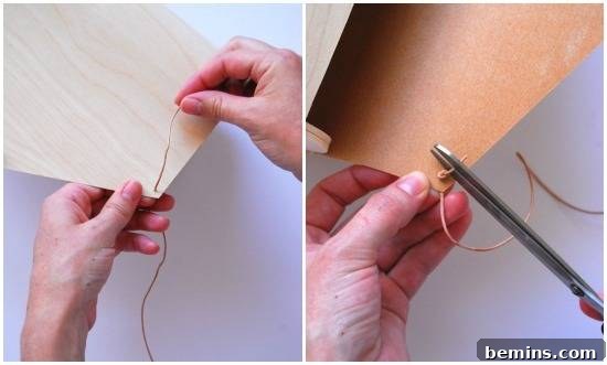 Someone is pulling a cord through a thin piece of wood, tying a knot in the cord, then clipping off the end of the cord.