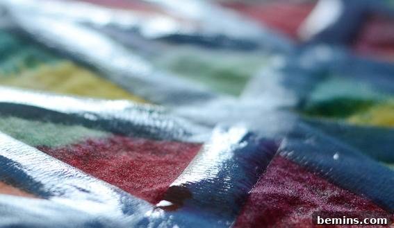 Blue painter's tape marks off lines on a piece of fabric with various colors on it.