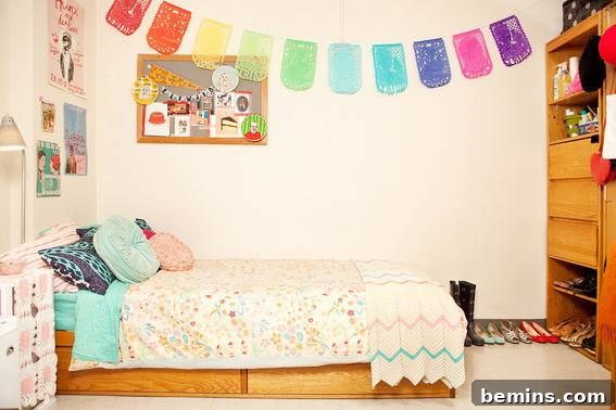A dorm room featuring a cot and a colorful hanging arch on the side wall, creating a whimsical and personalized touch.