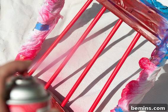 A person spray painting a chair red. Accenting with red paint.