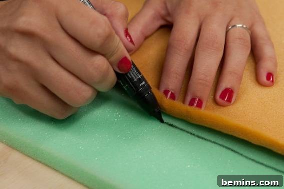 A woman drawing a line on a bright green spunge. Tracing foam for the new cushion.