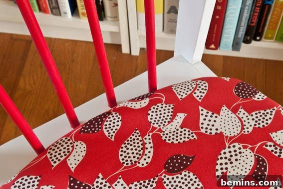 A dining chair is painted white with red back slats and a red and white cushion. Final product.