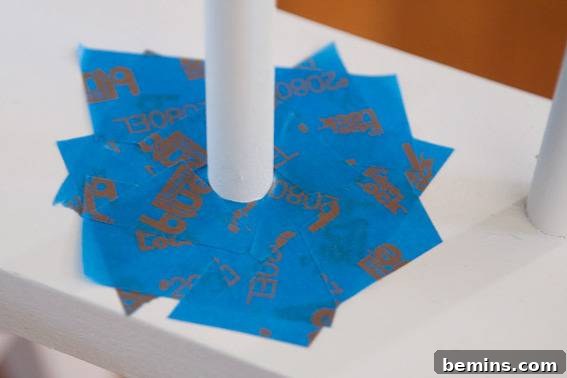 Pieces of blue paper or tape surround a white pole. Masking off spindles with tape.
