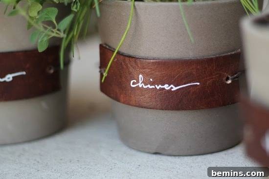 Leathercraft Dreams: 11 DIY Projects to Ignite Your Creativity 11 A beige flowerpot is seen close up with a brown leather label strapped on that says “chives” in white cursive with chives hanging down;other similar pots are next to it but not in focus and not seen in their entirety.