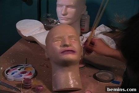 A table with a colourful paints, brush and dummy faces.