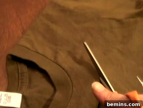 Person using scissors to cut a brown t-shirt near the neckline.