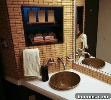 A sink sits on a white counter near a mirror and a tan tiled wall, featuring Jill McKeever's elegant bamboo vessel sink.