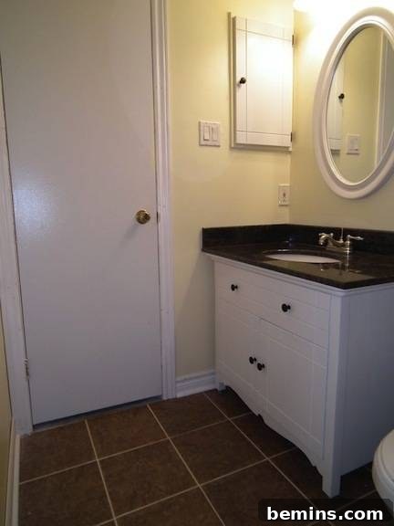A white bathroom has a black sink countertop, showcasing the transformed dresser as a stylish vanity.