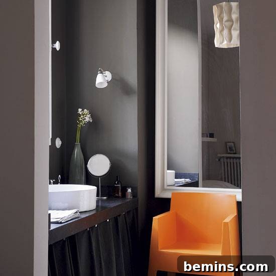 Dark Indulgence: 10 Bathrooms Embracing the Moody Palette 6 A dark bathroom brightened by a vibrant orange chair, adding a touch of personality.