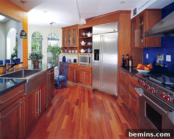 Stainless steel fridge next to a microwave in a kitchen with stainless steel appliances and wood floors.