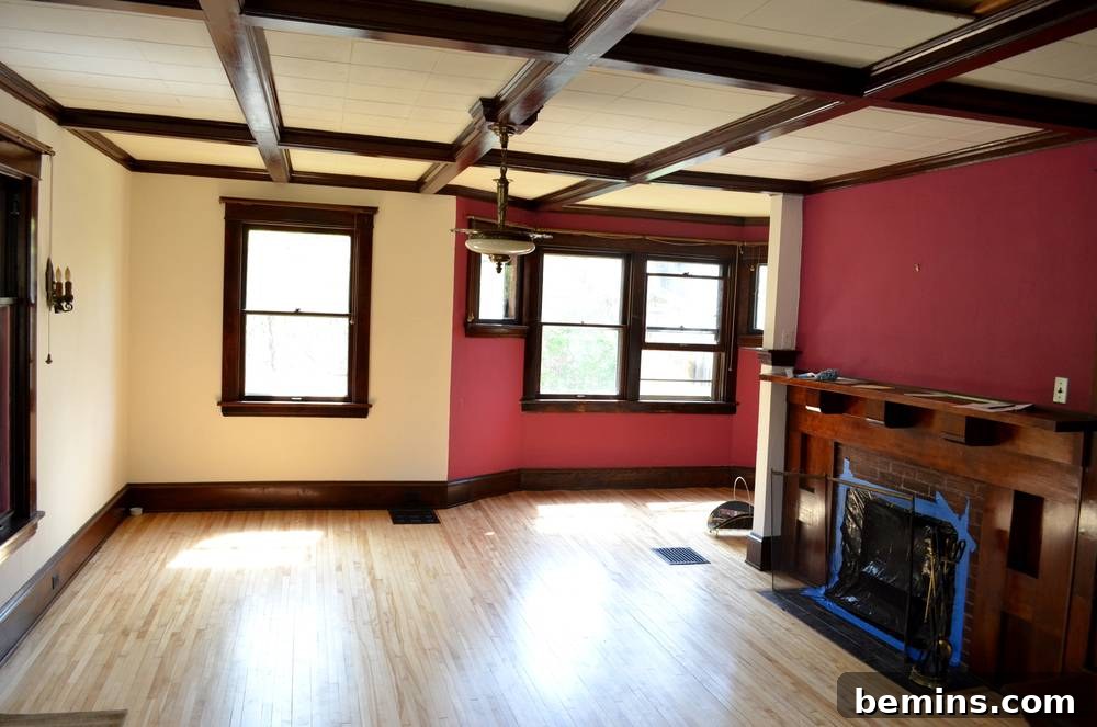 An empty wooden floored room with red and white wall and a fire place.
