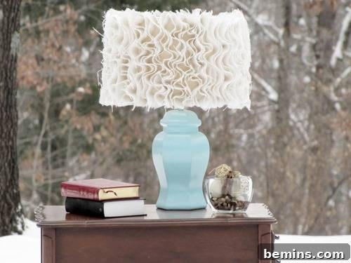 A blue lamp with a white lampshade sitting on a nightstand next to some books and a glass bowl.