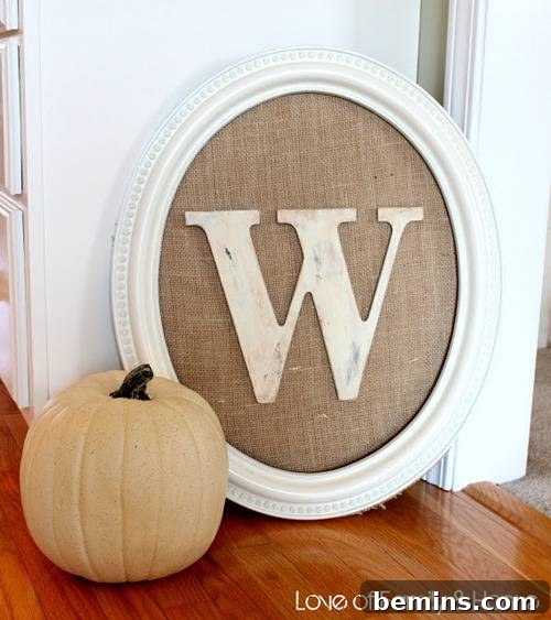 The letter W inside an oval frame near a pale pumpkin.