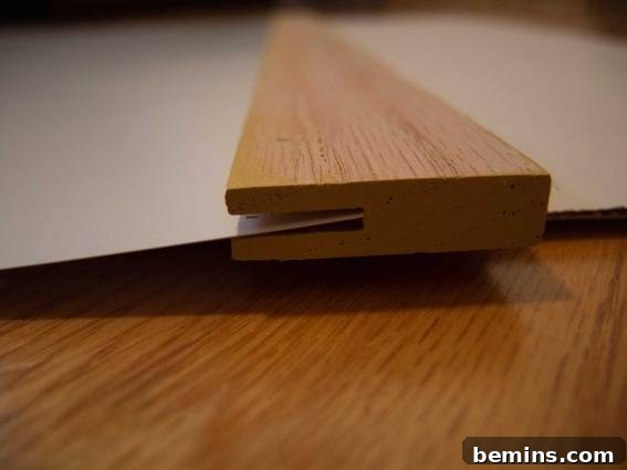 The poster being carefully inserted into the wooden slats of the DIY poster hanger.