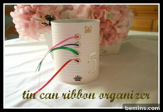A white tin can that has four holes with different colored ribbons coming from each hole. Ribbon organizer made from recycled soup can.