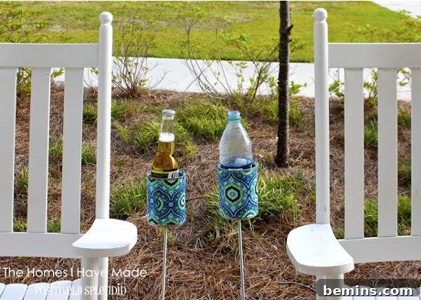 Plastic bottles in cup holders by white wood rocking chairs. Outdoor drink holder made from recycled soup can.