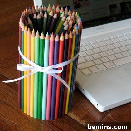 Pencils glued together to form a pencil holder next to a lap top. DIY pencil holder made from recycled soup can and colored pencils.