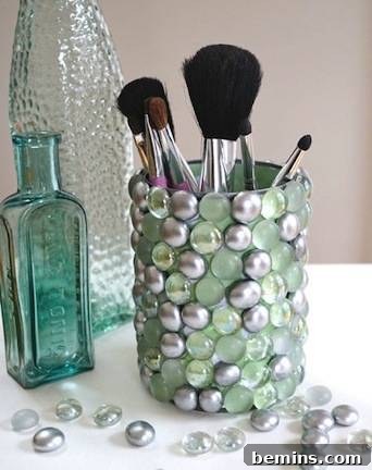 Several make up brushes are in a pearly blue cup. Blingy storage container made from recycled soup can.
