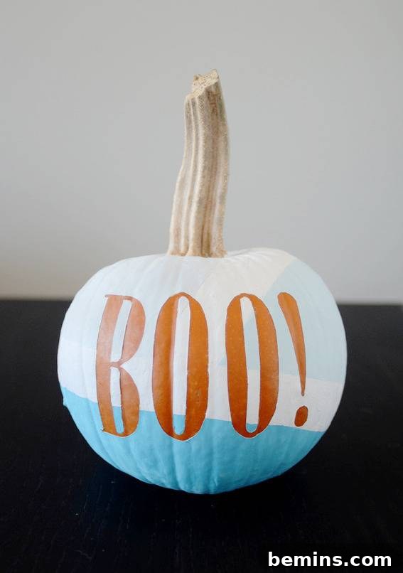A pumpkin painted white and blue with the word boo on it