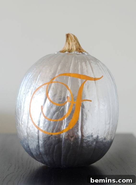A pumpkin that has been spray painted bright silver and has an f on it