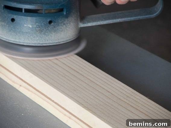 Craft a Rustic Chalkboard Card Display from Reclaimed Wood 10 A person uses a sander on a piece of wood. Sanding the wood board to create a smooth surface for painting.