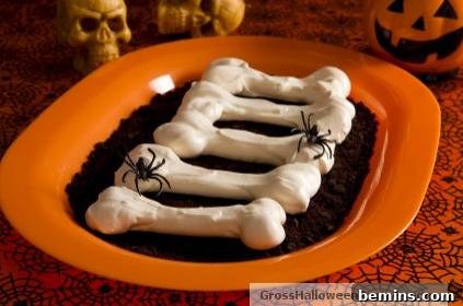Frosted bone cookies in cookie dirt with spiders on an oval plate.