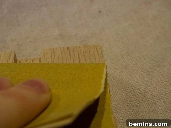 A person carefully sanding a piece of wood, ensuring a smooth and even surface for the final geometric trivet