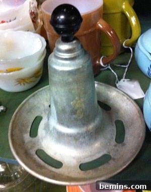 A vintage kitchen gadget with slots in the base and a black bulb on top of a cone.