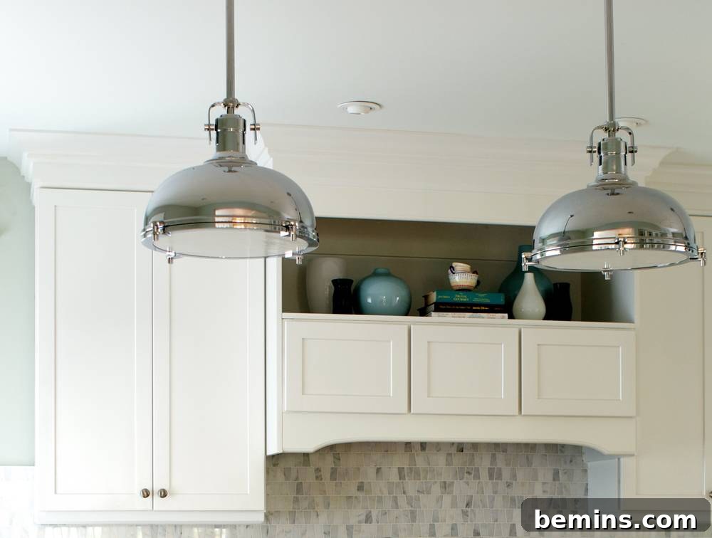 Two silver dome shaped lights hanging from a kitchen ceiling.