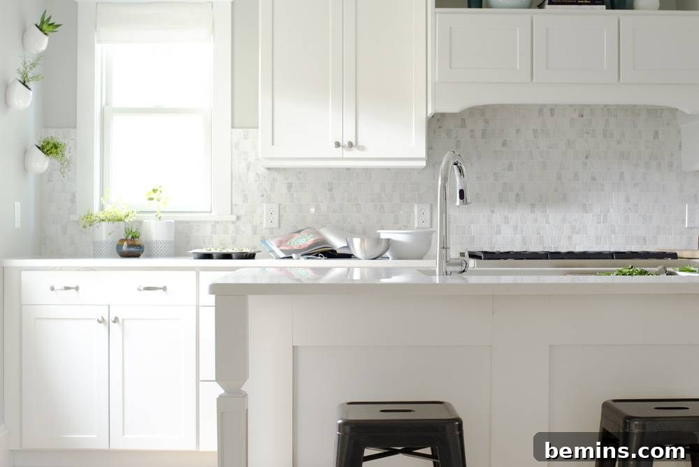 An all white kitchen with a sink and black chairs.