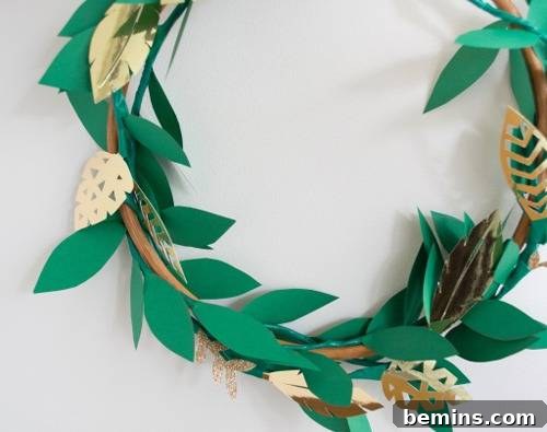 An elegant wood wreath frame adorned with green and gold paper leaves, creating a sophisticated Christmas decoration.