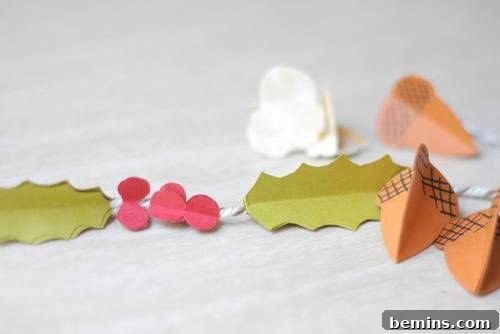 A charming paper garland featuring leaves, berries, and acorns strung together, perfect for adding a festive touch to any space.