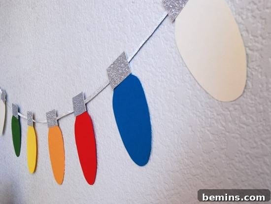 Colorful Christmas light like decorations are handing on the wall. A DIY Christmas light garland decorating a wall.