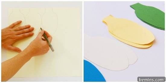 A person is drawing a light shape on the paper and placed the cut pieces of colorful light shape papers. Tracing and cutting paper for a DIY Christmas light garland.