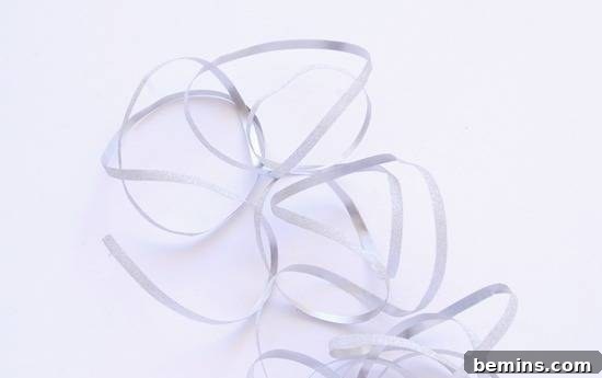 Ribbon is swirling around on a white background. Preparing the ribbon for a DIY Christmas light garland.